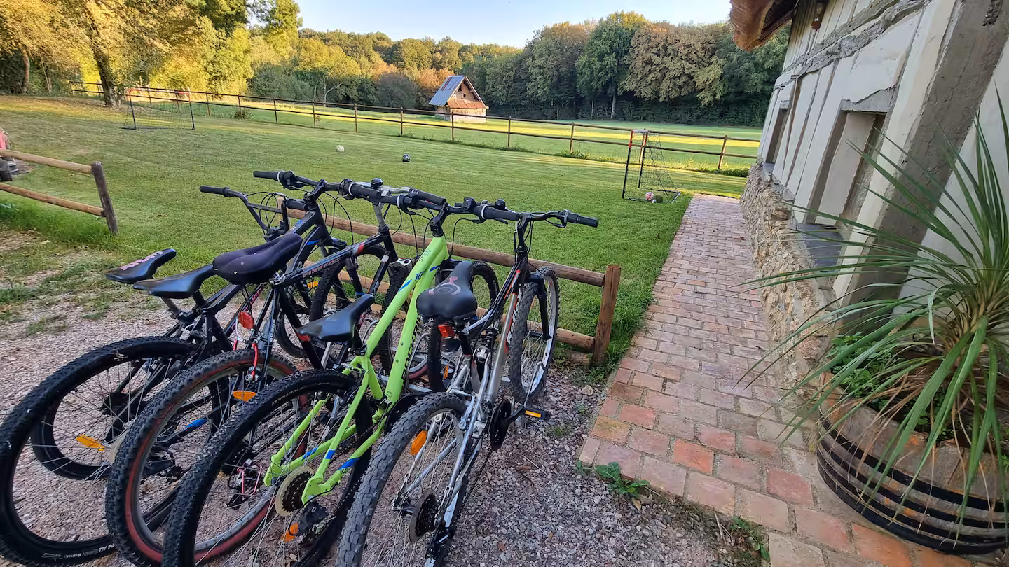 Plusieurs vélos garés contre une rambarde en bois, prêts à partir explorer le bocage normand.